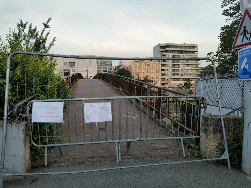 Photo prise côté Charenton de la passerelle d'Alfortville fermée de deux barrières entremêlées par des chaînes, avec affichage d'un arrêté et mention d'une déviation.